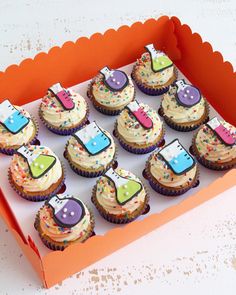 a box filled with lots of cupcakes covered in frosting and colorful decorations