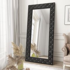 a large mirror sitting on top of a floor next to a chair