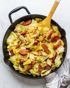 a skillet filled with cabbage and sausages on top of a white marble counter