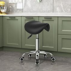 a kitchen with green cabinets and a black stool in front of a counter top on wheels