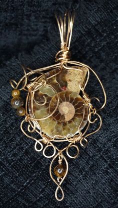 This pendant is a hand made bronze wire wrapped ammonite, accented with tiger eye beads.  This will be shipped with an eighteen inch length of satine cord, so that the length of the necklace can be adjusted.  Alternatively, a bronze chain can be fabricated for an additional charge.  You can see me make items like this live on my Twitch.tv channel at https://www.twitch.tv/growlingmousestudio Hand Wrapped Copper Gold Necklace, Hand Wrapped Gold Copper Necklace, Gold Amulet Style Hand Wrapped Necklace, Gold Hand Wrapped Amulet Necklace, Gold Amulet Necklace Hand Wrapped, Bronze Spiral Wire Wrapped Jewelry, Bronze Wire Wrapped Spiral Jewelry, Spiral Wire Wrapped Brass Jewelry, Spiral Brass Wire Wrapped Jewelry