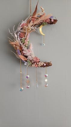 the moon is hanging on the wall with beads and feathers attached to it's side