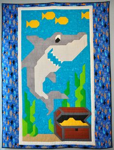 a quilted wall hanging with an image of a shark and fish in the water