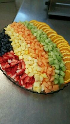 a platter filled with sliced fruit on top of a metal counter