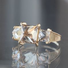 three stone ring sitting on top of a reflective surface