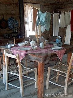 the table is set for four with dishes on it and clothes hanging up to dry