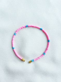 Handcrafted pink and blue beaded anklet/bracelet. Made using small colourful round glass beads and finished with a gold-plated barrel clasp closure. Pair it with our matching Necklace.  * Weight: 3g   * Width: 5mm/2mm  * Made in UK  * Code: 111APBS The very best in unique, handmade pieces from BAM-BAM, our anklets and bracelets make great accessories for the beach, festival or club. These small beads have a dainty appearance and can take your best looks from day to night. Pink Tiny Beads Anklets For Summer, Pink Anklets With Tiny Beads For Summer, Pink Beaded Anklets For Summer, Pink Beaded Summer Anklets, Adjustable Pink Anklet With Colorful Beads, Summer Pink Anklet With Colorful Beads, Summer Pink Beaded Bracelets With Heart Beads, Pink Heishi Beads For Beach, Handmade Pink Anklets For Beach