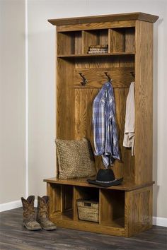 a wooden bench with a hat, coat rack and boots next to it on the floor