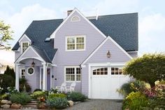 a large house with lots of plants and flowers in front of the garage door is shown