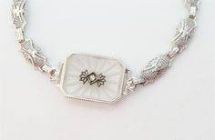 This intricately crafted Camphor Glass bracelet has a lovely sunburst pattern etched into the glass. It is made of 14kt white gold filigree with a diamond center and is a true Art Deco period bracelet. Camphor glass is clear glass that has been treated with hydrofluoric acid vapors to give it a frosted, whitish appearance. It is 6.75" long, it is possible to lengthen it approx. .25" with adding a jump ring to the end , the center piece is .75" long x 5/8" wide each piece of the panel is 1/4" wide Total weight is 7gr.  Shipping INCLUDES INSURANCE on the total value I am a certified Gemologist and have sold antique and estate jewelry for over 20 years, so please feel confident in your purchase and comfortable to take this to a jeweler by your home to have it checked out. Look at our feedback Diamond Intaglio Jewelry, Round Diamond Intaglio Jewelry, Fine Jewelry Diamond Intaglio, Fine Jewelry Diamond With Intaglio Detail, Fine Diamond Intaglio Jewelry, White Intricate Bracelet Jewelry, White Intricate Design Bracelet, Art Deco Engraved White Gold Jewelry, Engraved White Gold Art Deco Jewelry