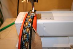 the sewing machine is next to an orange and blue ribbon on it's side