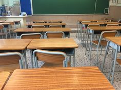 an empty classroom filled with wooden desks and chairs