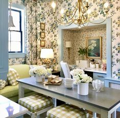 a dining room with floral wallpaper and chandelier hanging from the ceiling above it