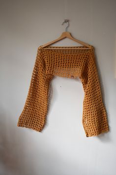 an orange knitted top hanging on a white wall