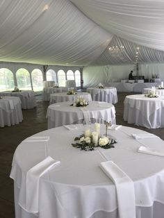 tables with white linens are set up in a tent