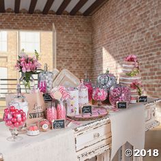 a table with candy and candies on it in front of a brick wall at a wedding