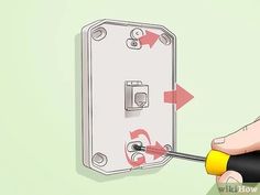 a person using a screwdriver to fix a light switch