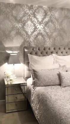 a white bed sitting in a bedroom next to a nightstand with a lamp on top of it