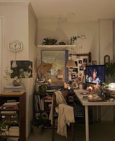 a room with a desk, computer and shelves filled with plants on the wall next to it