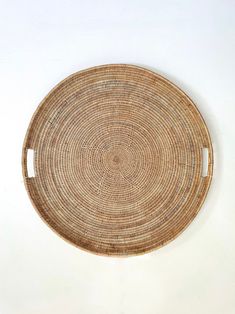 a round woven basket hanging on the wall in front of a white wall and floor