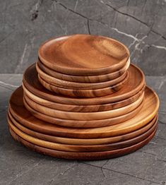 a stack of wooden plates sitting on top of a stone floor next to a wall