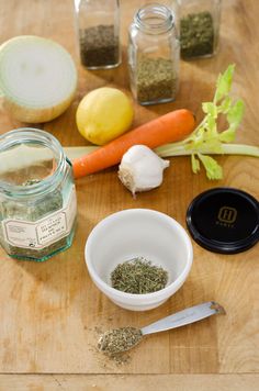 spices, herbs and lemons sit on a wooden table next to glass jars with labels