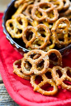 some pretzels are sitting in a bowl on a red cloth next to a black pan