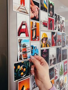 someone is placing pictures on the side of a refrigerator with magnets attached to it