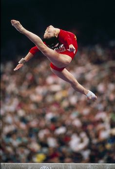 a woman is performing on the balance beam in front of an audience