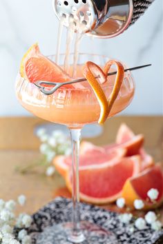 a drink being poured into a glass with grapefruit and orange slices