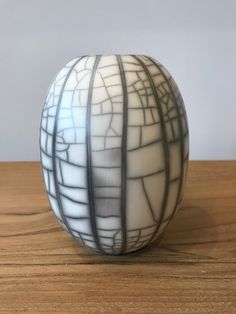 a white and black vase sitting on top of a wooden table