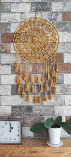 a clock sitting on top of a wooden table next to a wall hanging with tassels