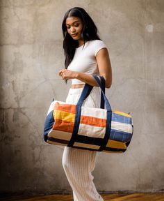 a woman carrying a multicolored duffel bag