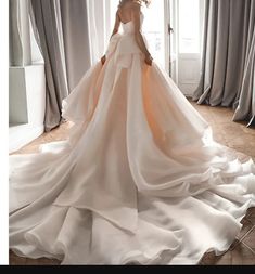 a woman standing in front of a window wearing a wedding dress