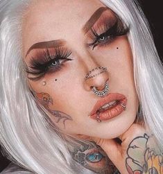 a woman with white hair and piercings on her face is posing for the camera