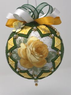 a glass ornament with a yellow rose painted on the front and side, hanging from a string