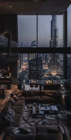 a living room filled with lots of furniture and tall buildings in the background at night