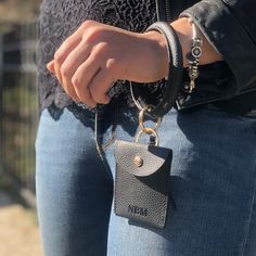 This faux leather bangle is perfect for bringing with you on the go! You can hang your keys, Cuticle Buddy® and/or our new portable glass nail files off of it. The button closure wallet can store credit cards or money. Wear as a bracelet or hold like a purse! Features gold toned metal details and a tassel addition. Vegan. Made from 100% polyurethane leather. Cuticle Buddy® not included. Adjustable Wristlet With Interior Key Chain Holder For Travel, Trendy Adjustable Wristlet With Card Slots, Trendy Wristlet With Card Slots For Everyday Use, Trendy Everyday Wristlet With Card Slots, Trendy Everyday Rectangular Wristlet, Adjustable Wristlet With Cell Phone Pocket For Gifts, Black Wristlet With Cell Phone Pocket For Gift, Black Wristlet With Cell Phone Pocket As Gift, Trendy Wristlet With Keychain For Everyday