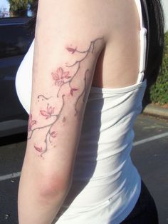 a woman with a tattoo on her arm is standing in front of a parked car