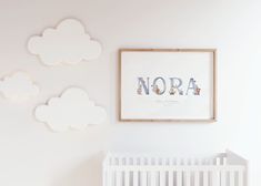 a baby's room with white crib and clouds on the wall above it