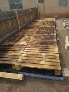 a wooden deck is being built in front of a house with wood slats on the ground