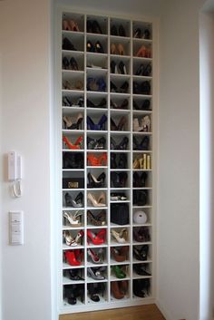 a white bookcase filled with lots of shoes next to a wall mounted light switch