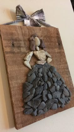 a wooden plaque with rocks and a bow on it