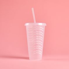 a plastic cup with a straw in it on a pink background