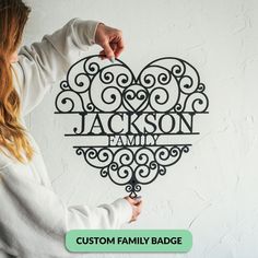 a woman holding up a metal heart with the word, custom family badge on it