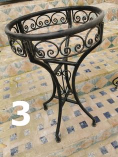 a wrought iron plant stand sitting on top of a tiled floor next to some steps