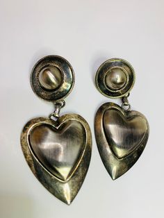 Large dangling double heart with antique silver tone on the outer and brushed silver tone on the inside pierced earrings. Measurements are 2 1/2 inches long by 1 1/4 inches wide. In good condition. Vintage Silver Heart Metal Earrings, Vintage Silver Metal Heart Earrings, Vintage Metal Heart Earrings, Vintage Silver Heart Earrings In Metal, Silver Heart-shaped Metal Earrings, Nickel-free Silver Metal Heart Earrings, Vintage Silver Heart Earrings, Silver Metal Heart Earrings For Anniversary, Vintage Nickel-free Heart Earrings