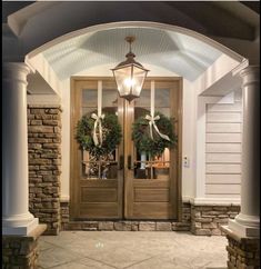 two wreaths are hanging on the front door of a house with an arched glass entryway