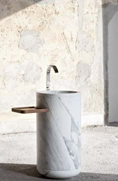 a white marble sink sitting on top of a counter next to a wall mounted faucet