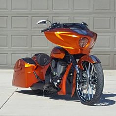 an orange motorcycle is parked in front of a garage door and it's lights on